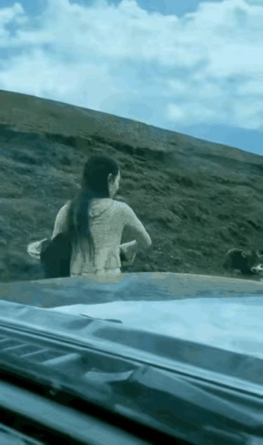 这个女子的胆量还真不小，居然敢拿一件衣服去吓唬这个动物，一般的女子遇到这样的情况