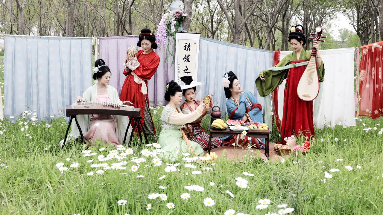 4月26日，淮阳龙湖南坛公园几位身穿汉服的女子演绎了古代裙幄宴的场景，草地上野花
