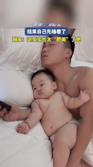 一位爸爸本想哄宝宝睡觉，结果自己先睡着了。画面里的宝宝肉嘟嘟的，浑身圆滚滚的，小