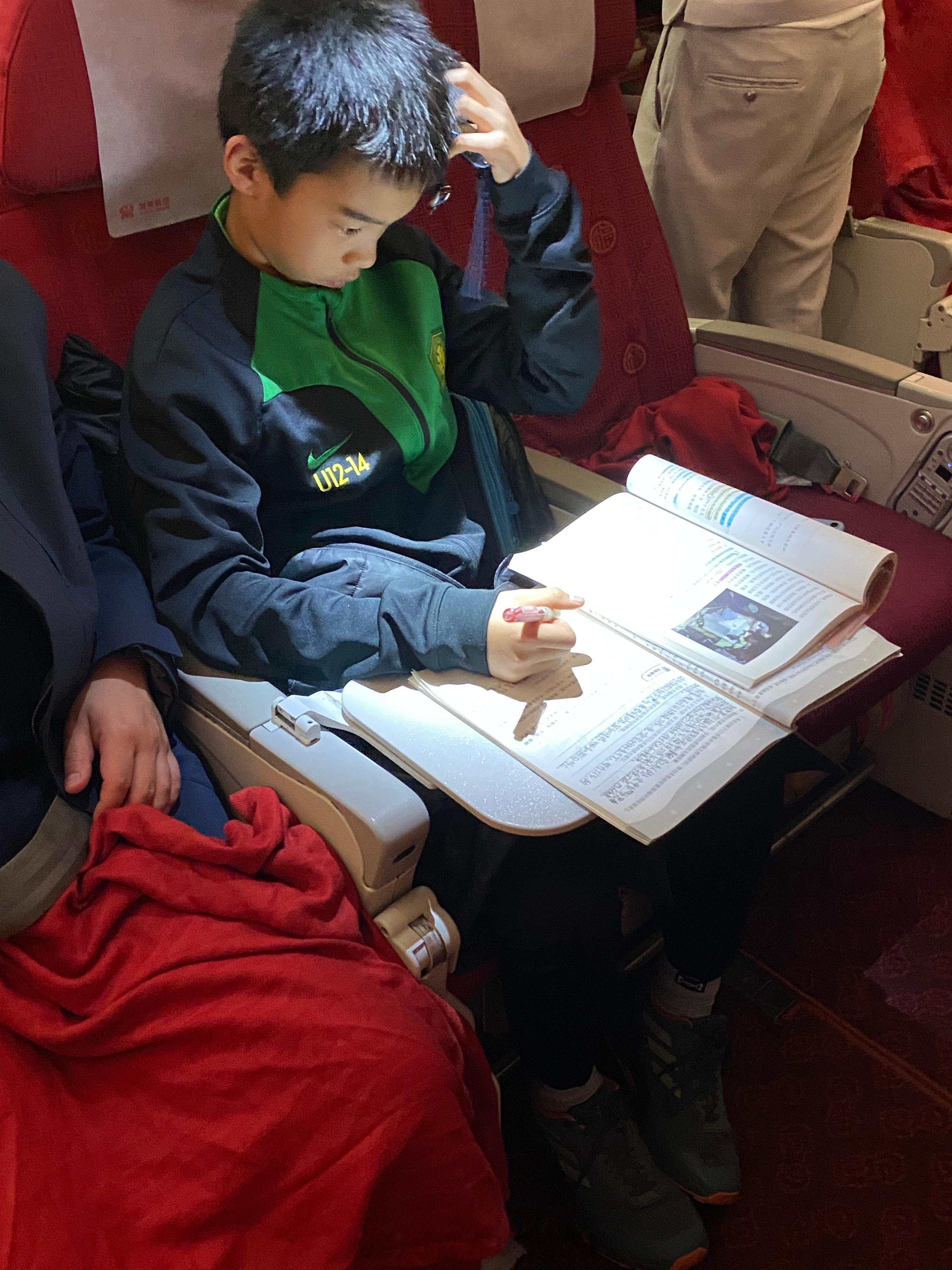 又到开学季， u13梯队球员在冬训回京的航班上，利用最后的时间完成假期作业[收到