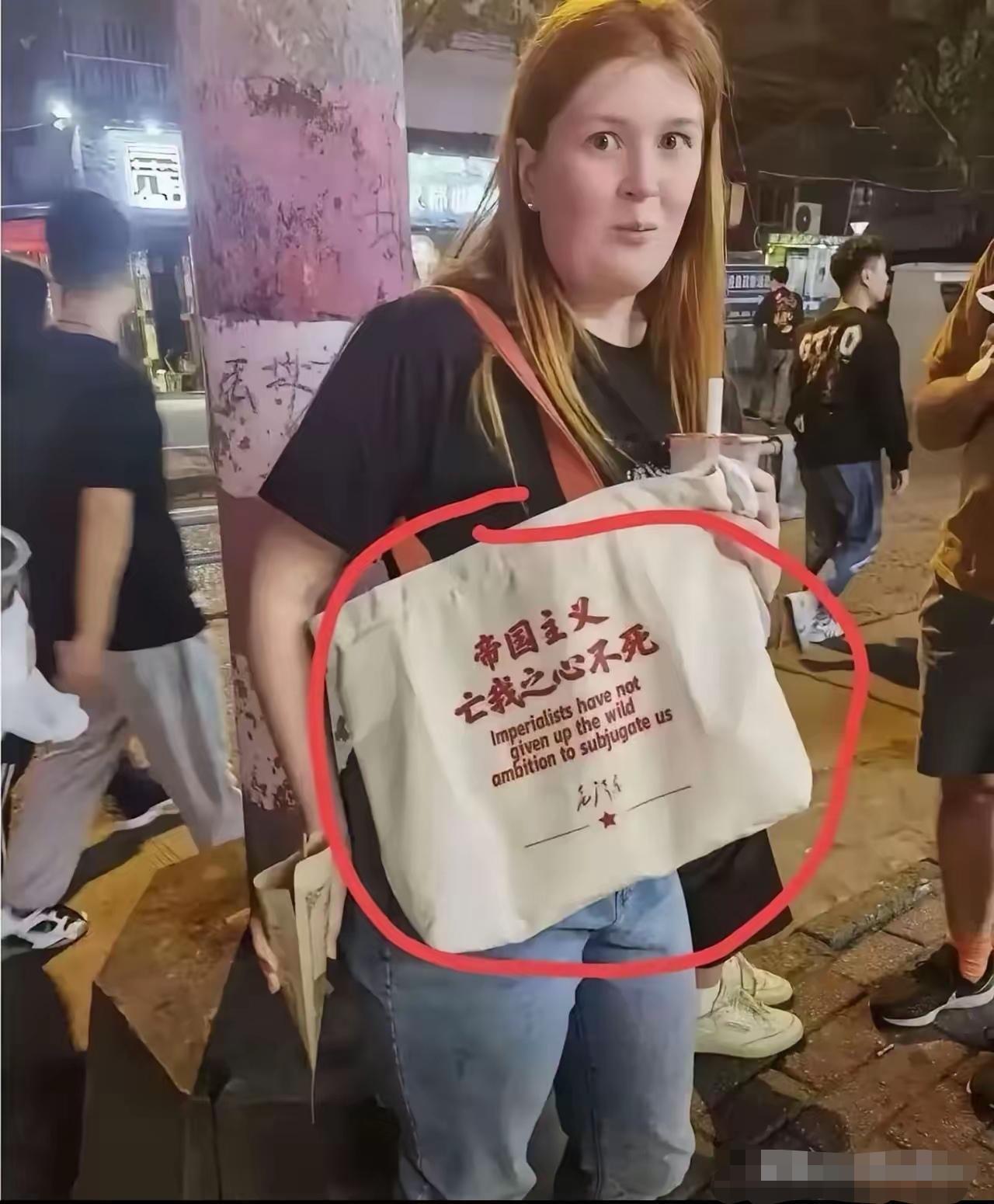 必须给这个外国美女点赞，她背的帆布包上用中英双语写着：帝国主义亡我之心不死。最下