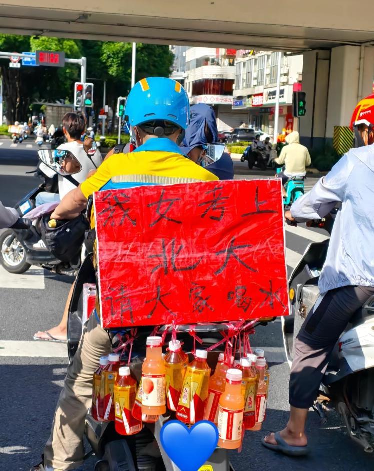 广西闪送员在电瓶车上挂满饮料，红纸写着“女儿考上北大，请大家免费喝水”（可见图片