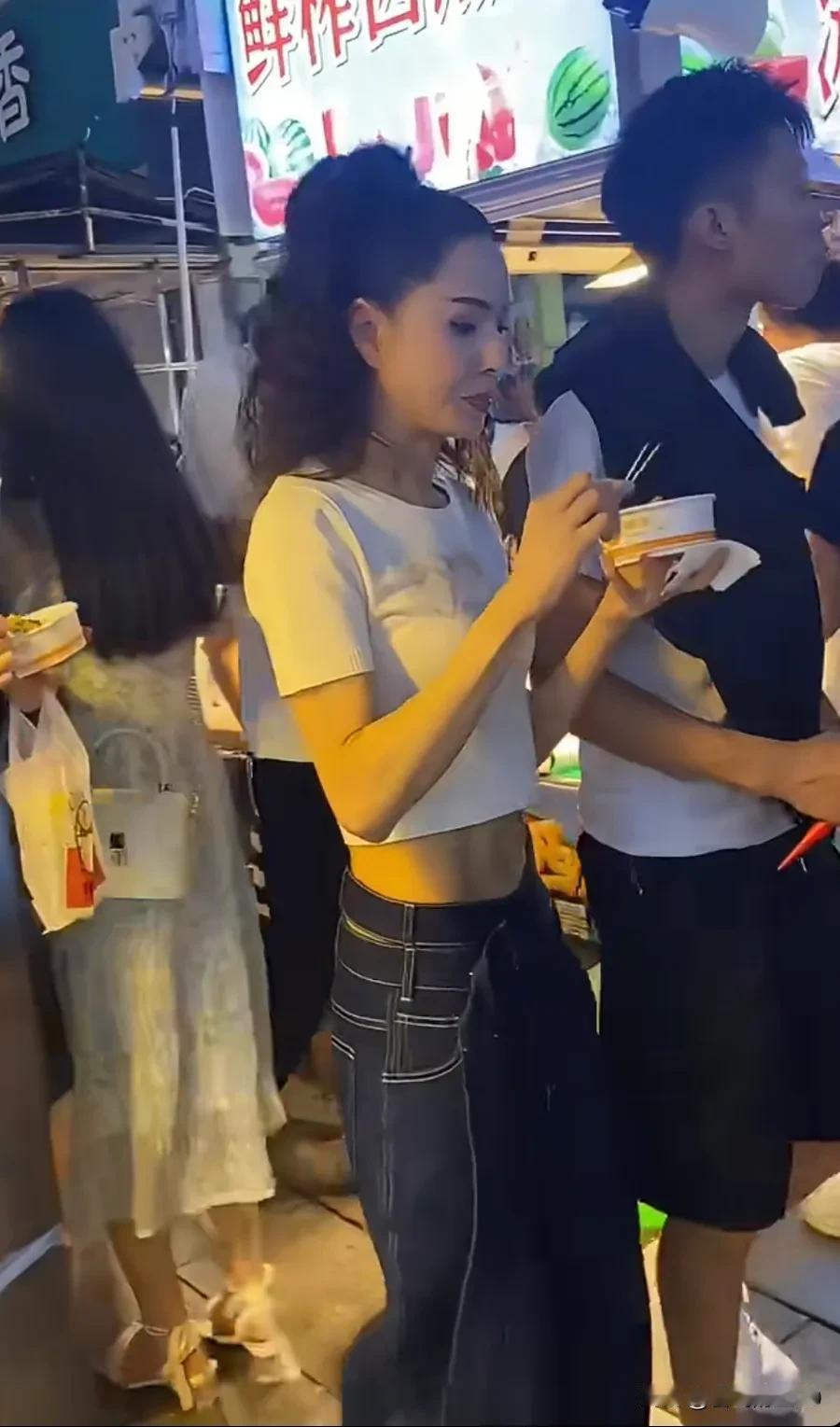 李若彤逛夜市，手里拿个碗边走边吃，估计太辣不停擦鼻。57岁的她皮肤紧致，身材保持