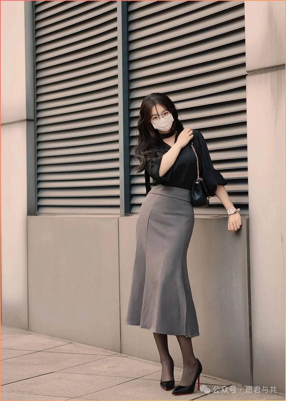 她留着微卷的深棕长发，搭配圆框眼镜与白色口罩，眉眼间透着知性气质，颈间的黑色ch