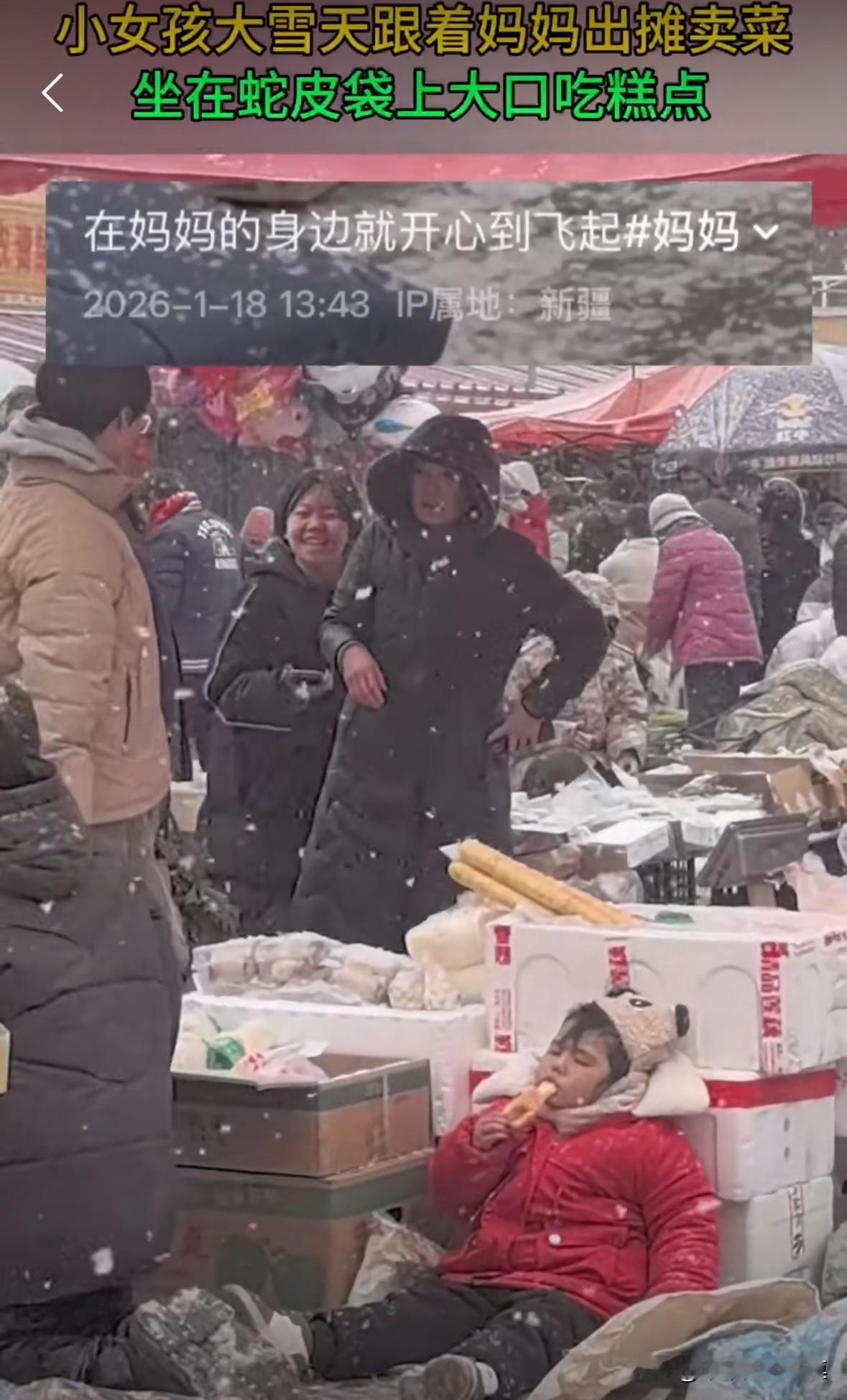 女孩下雪天跟着妈妈一起出门摆摊卖菜，妈妈买菜，女孩坐在蛇皮袋上吃着零食！
生活虽
