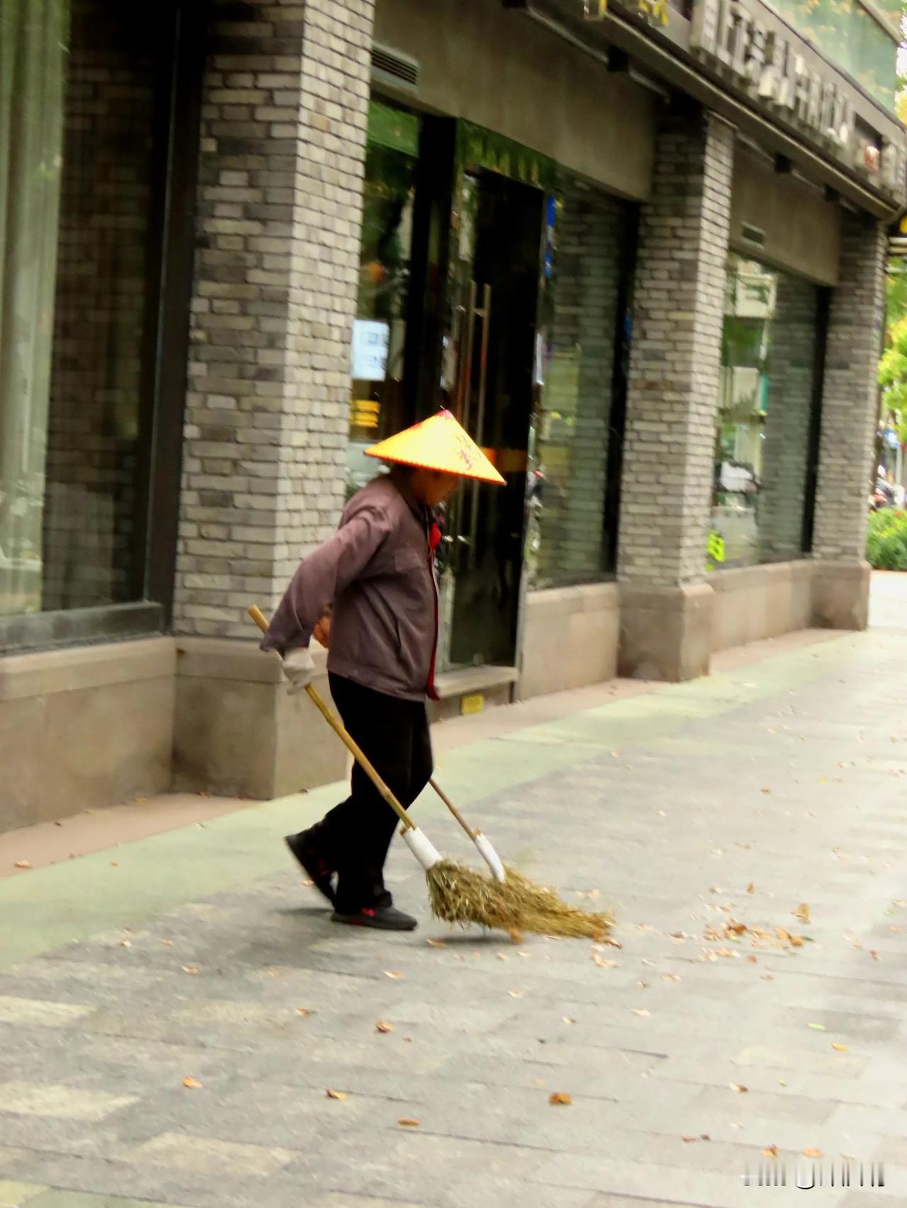 秋日清晨，环卫工人在落叶中辛勤劳作，守护城市整洁。