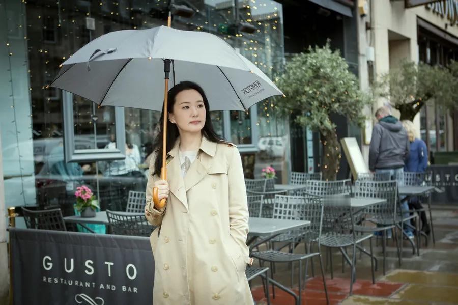 54岁柏林影后咏梅，在爱登堡雨中漫步！这位年过半百的女子，一身经典卡其色风衣，简