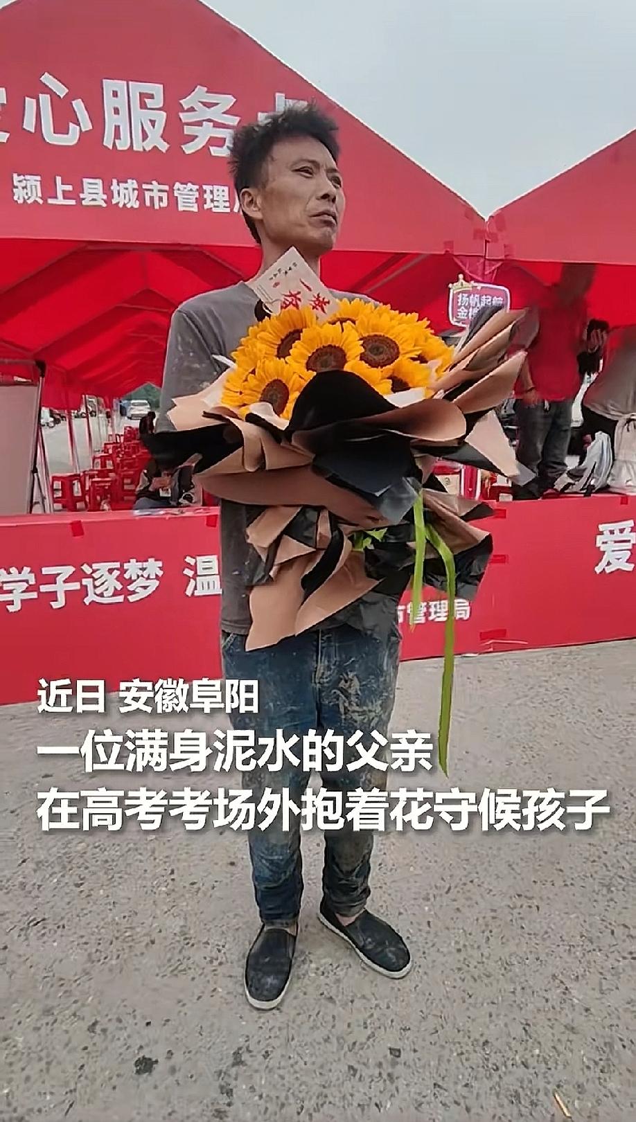 在考场外，这一幕令人动容，一位父亲，怀里抱着一大束向日葵，满身都是泥巴，还穿着一