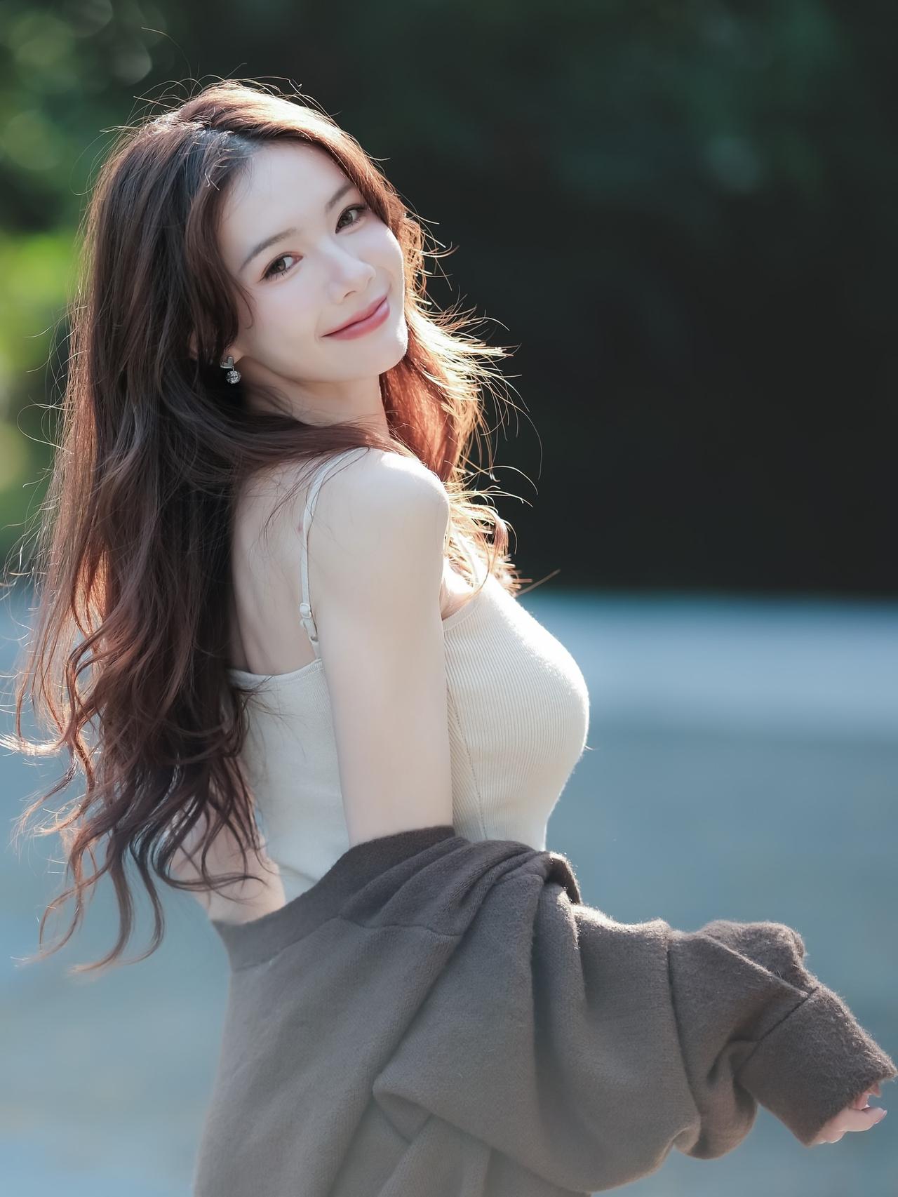 阳光下的温柔微笑，长卷发随风飘逸，简约穿搭尽显自然美。