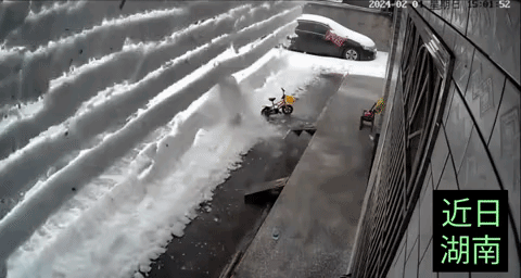 没想到湖南会下这么大的雪，一位女子在家中扫雪，突然房顶上的雪全部滑落，像雪崩一样
