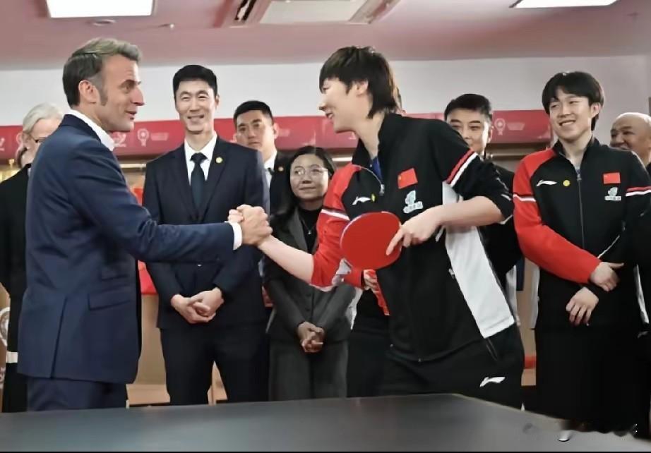 王曼昱给所有运动员上了一课

王曼昱站在马克龙旁边握手时，左手握球拍，右手从容舒