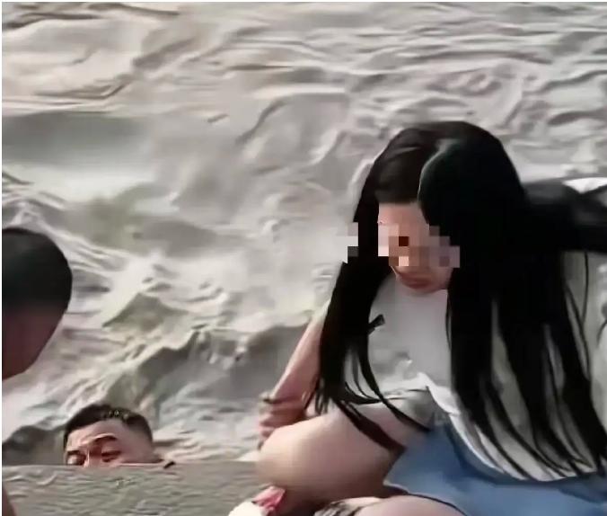 武汉汉口，一女子站在江滩边，丈夫给她拍照，突然丈夫扔下手机，纵身跳入江里。而妻子