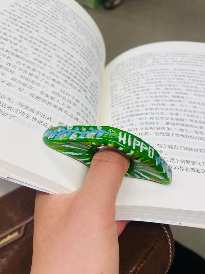在指尖的巧思中，石塑粘土化作智慧的结晶。一个简单而巧妙的压书环，解决了单手拿书时
