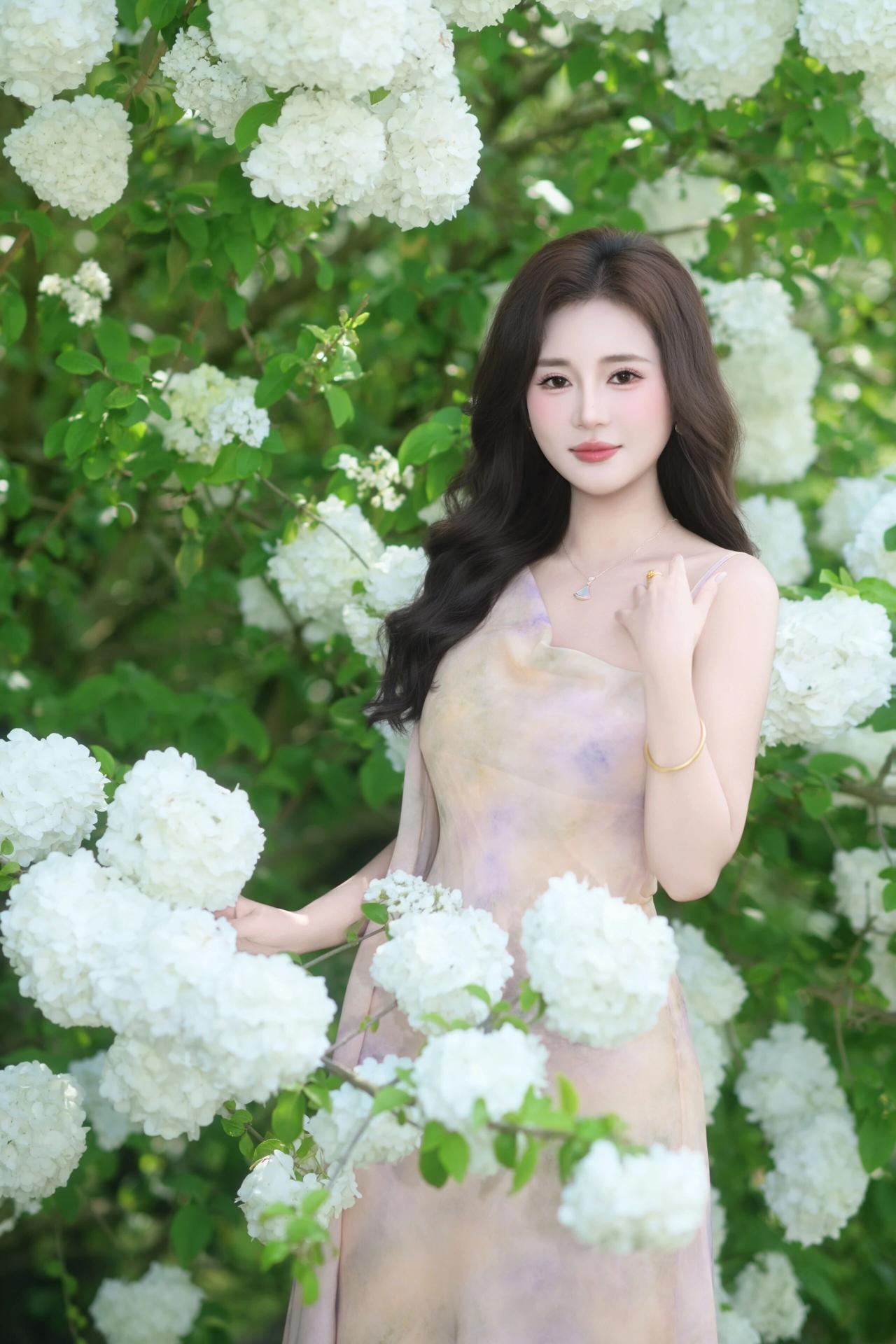 她身着一袭浅杏色的晕染吊带长裙，面料轻盈飘逸，勾勒出曼妙身姿，尽显温柔雅致。一头