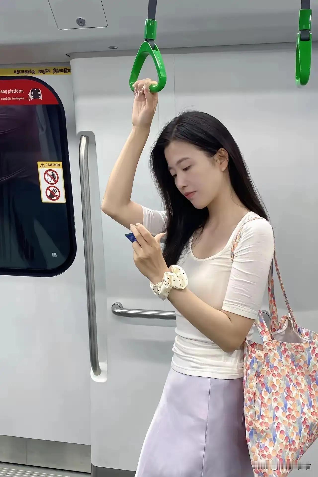 地铁上的优雅一刻：手提包与手机相伴，轻松出行。