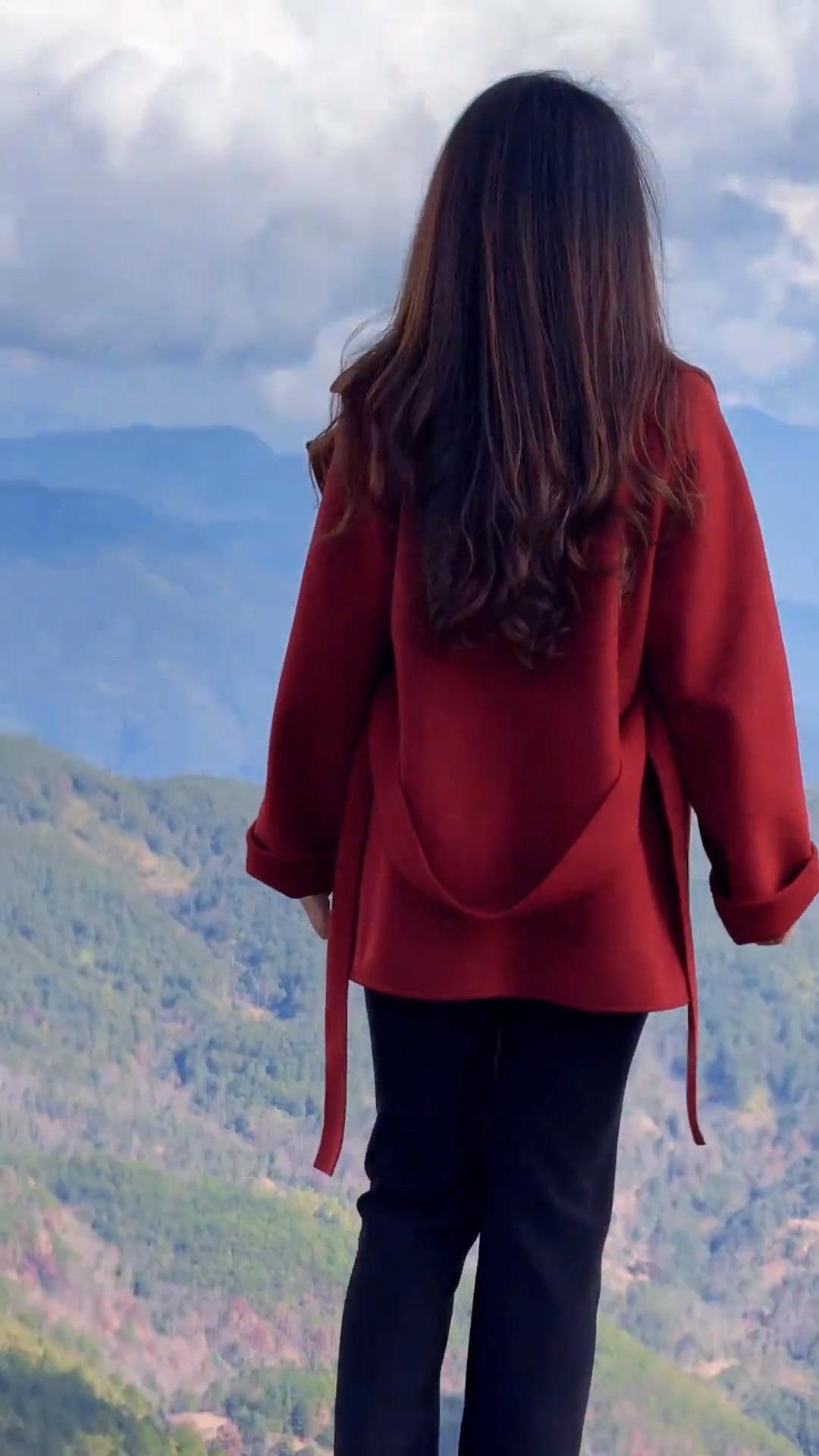 红衣少女背对镜头，眺望山峦起伏，心旷神怡。