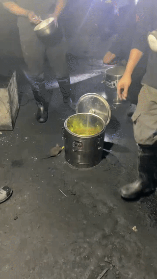 一群煤矿工人正在工作层休息吃饭。
他们吃的饭菜看起来非常简单，就是一些青菜和大米
