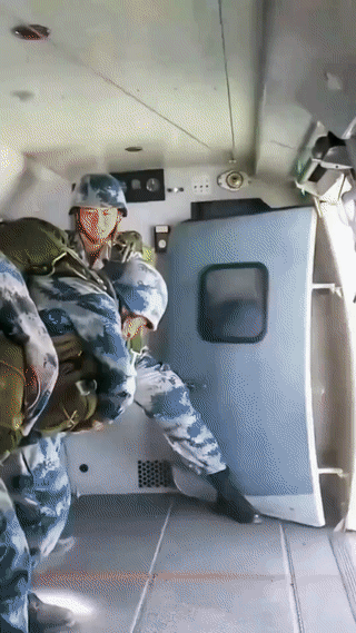 这是中国空降兵正在飞机上进行低空跳伞训练。
原来他们身上的降落伞是跳下飞机后自动