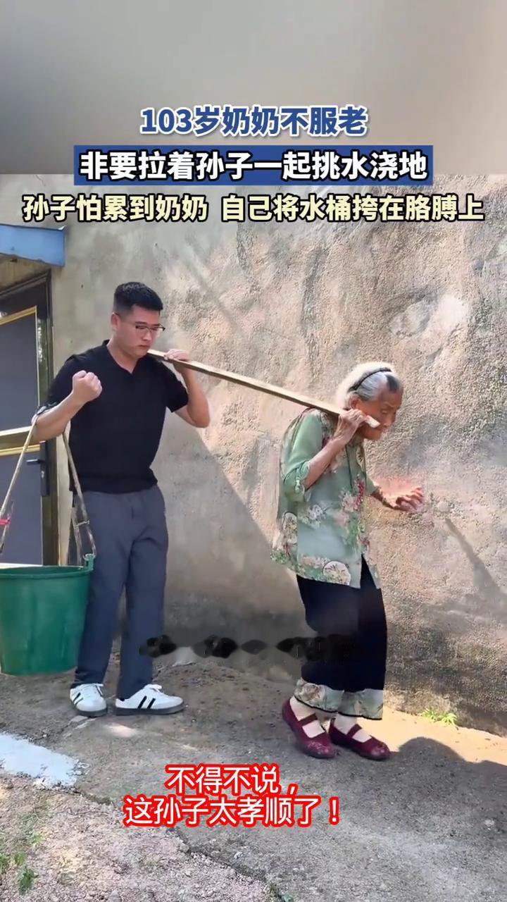 103岁奶奶不服老，非要拉着孙子一起挑水浇地。孙子怕累到奶奶自己将水桶挎在胳膊上