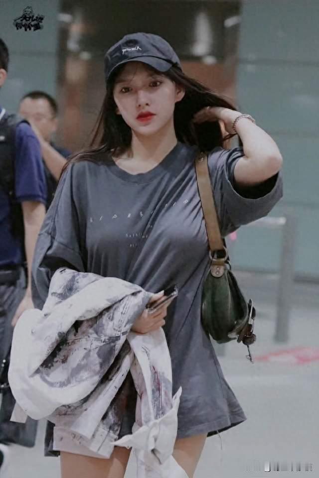 程潇机场路透生图！灰 T 恤裙紧身勾勒曲线，棒球帽红唇太会穿