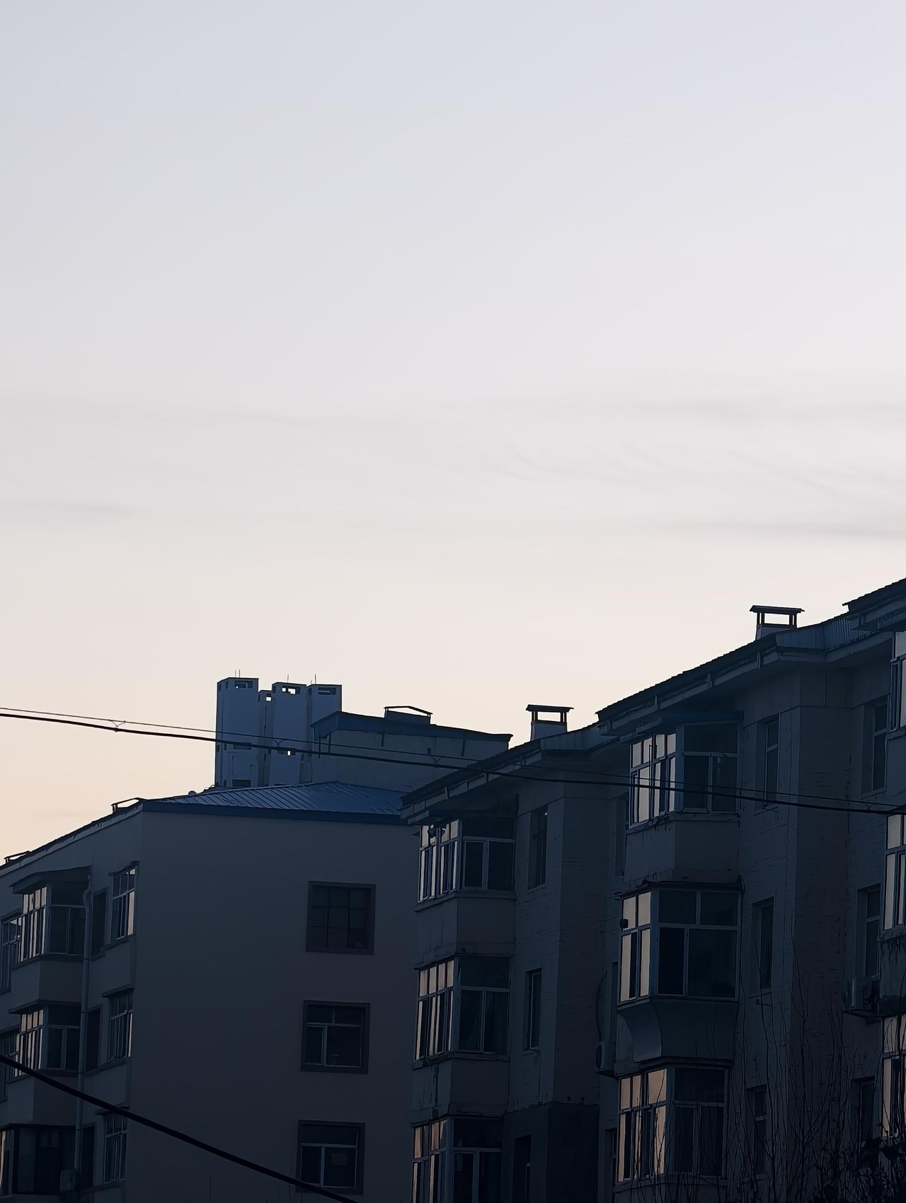 晚影
 
傍晚的风掠过楼檐，带着北方冬日特有的清冽。老旧居民楼的轮廓在渐暗的天色