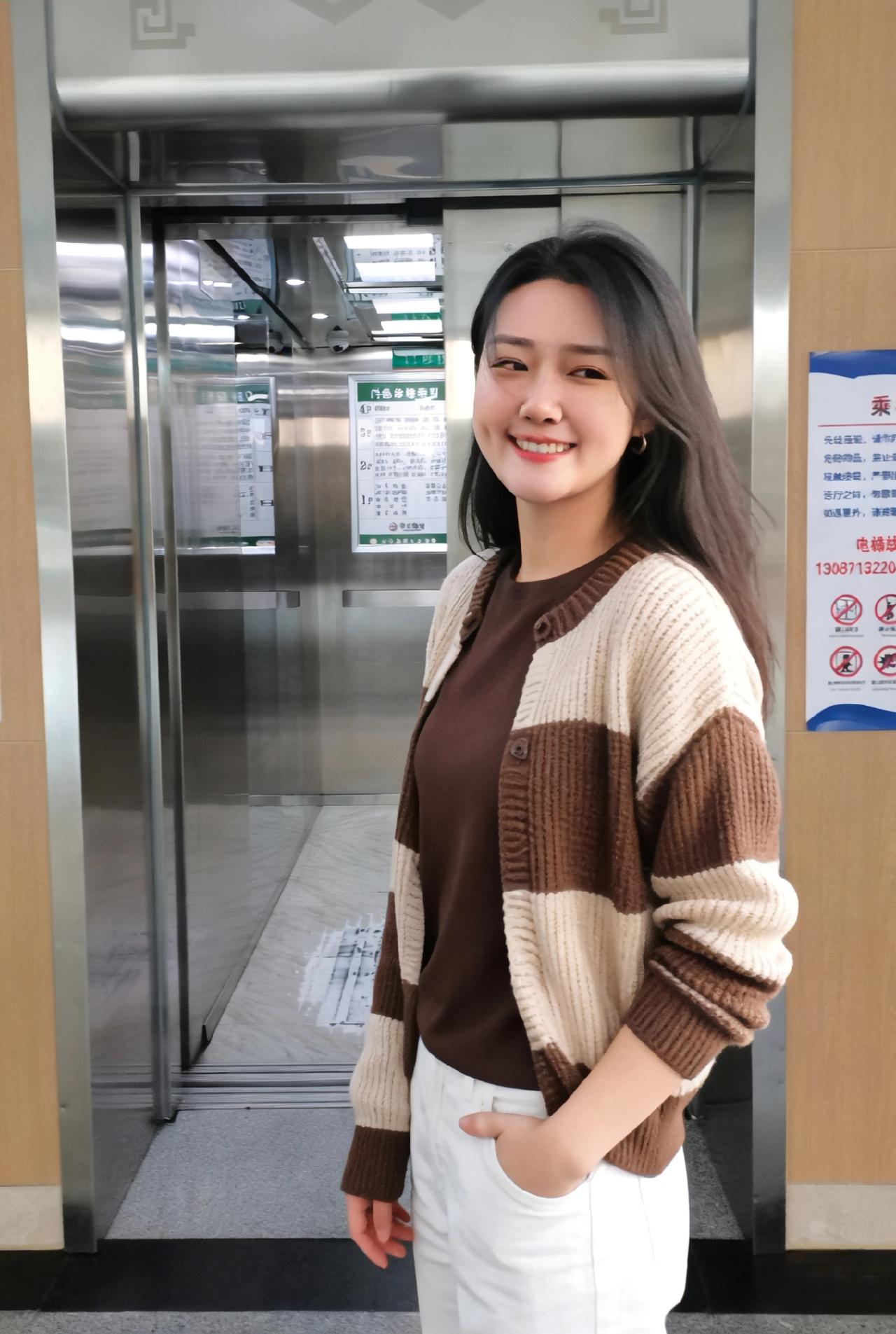 电梯门畔晓光融，女子嫣然立金风。
棕白开衫裁软玉，素白长裤曳晴虹。
眉弯浅带三分