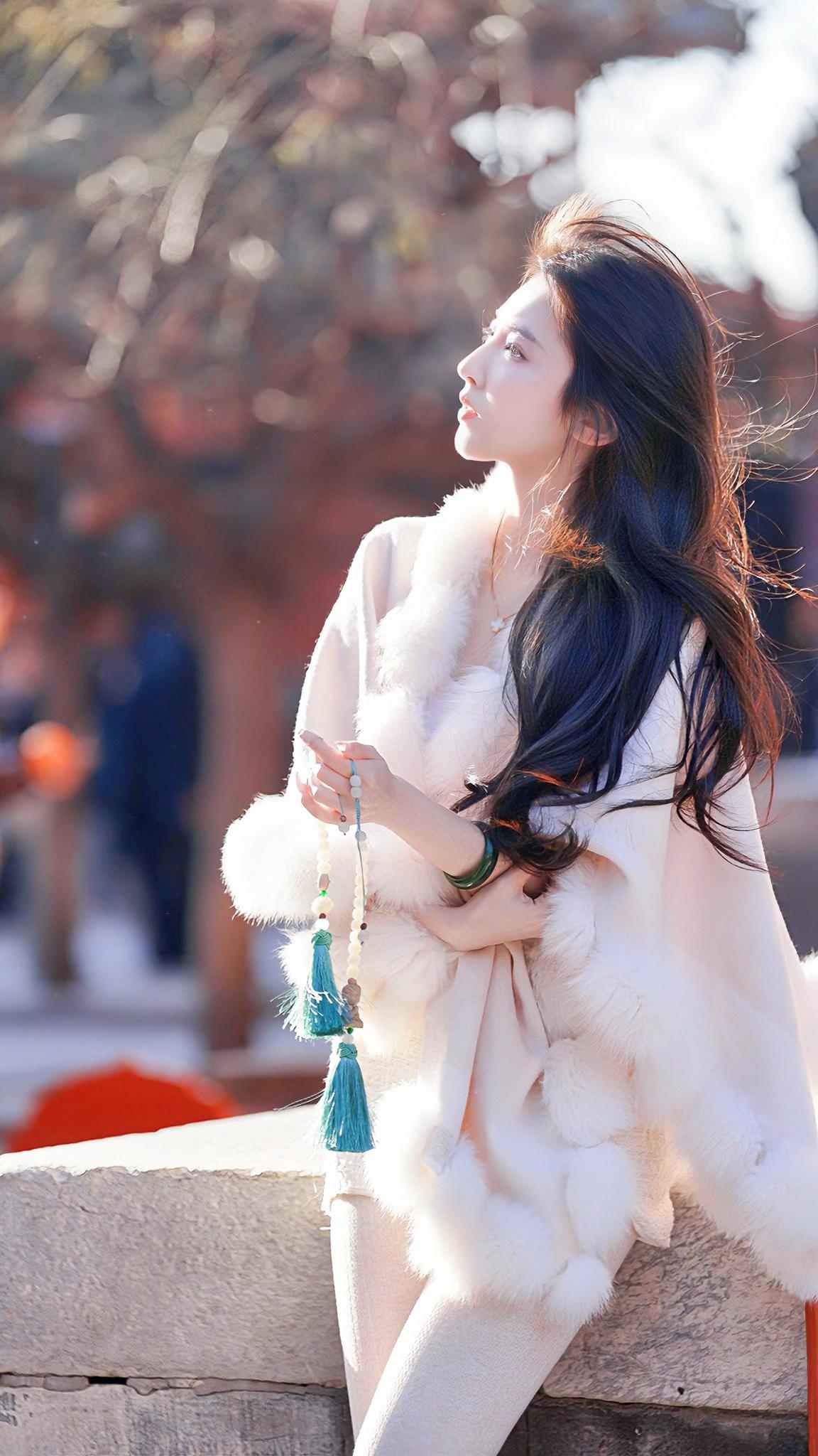 冬日暖阳下，优雅女子倚栏而立，长裙飘飘，尽显温柔与浪漫。