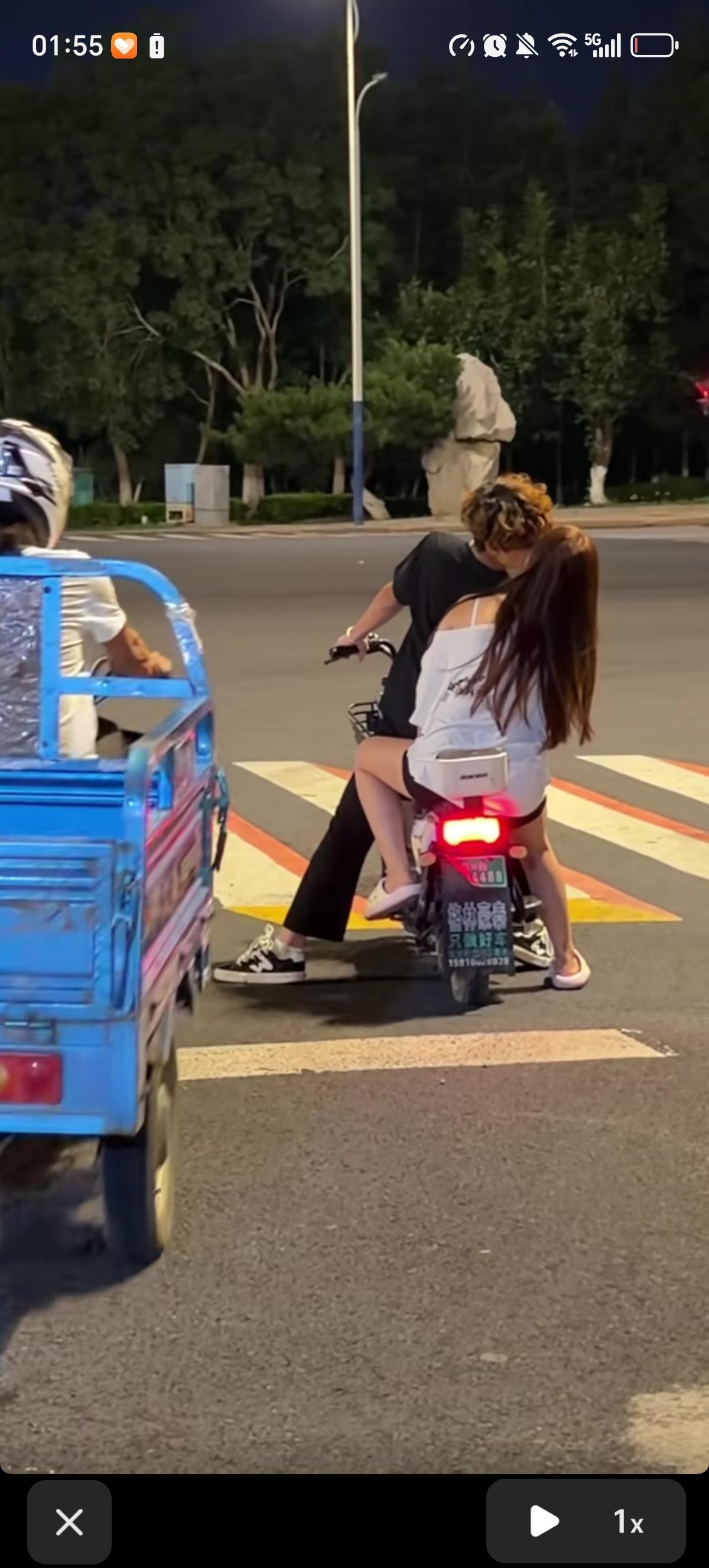 年轻小伙骑电动车过马路也不忘了亲吻后座的女朋友，丝毫没察觉危险正在靠近。开三轮车