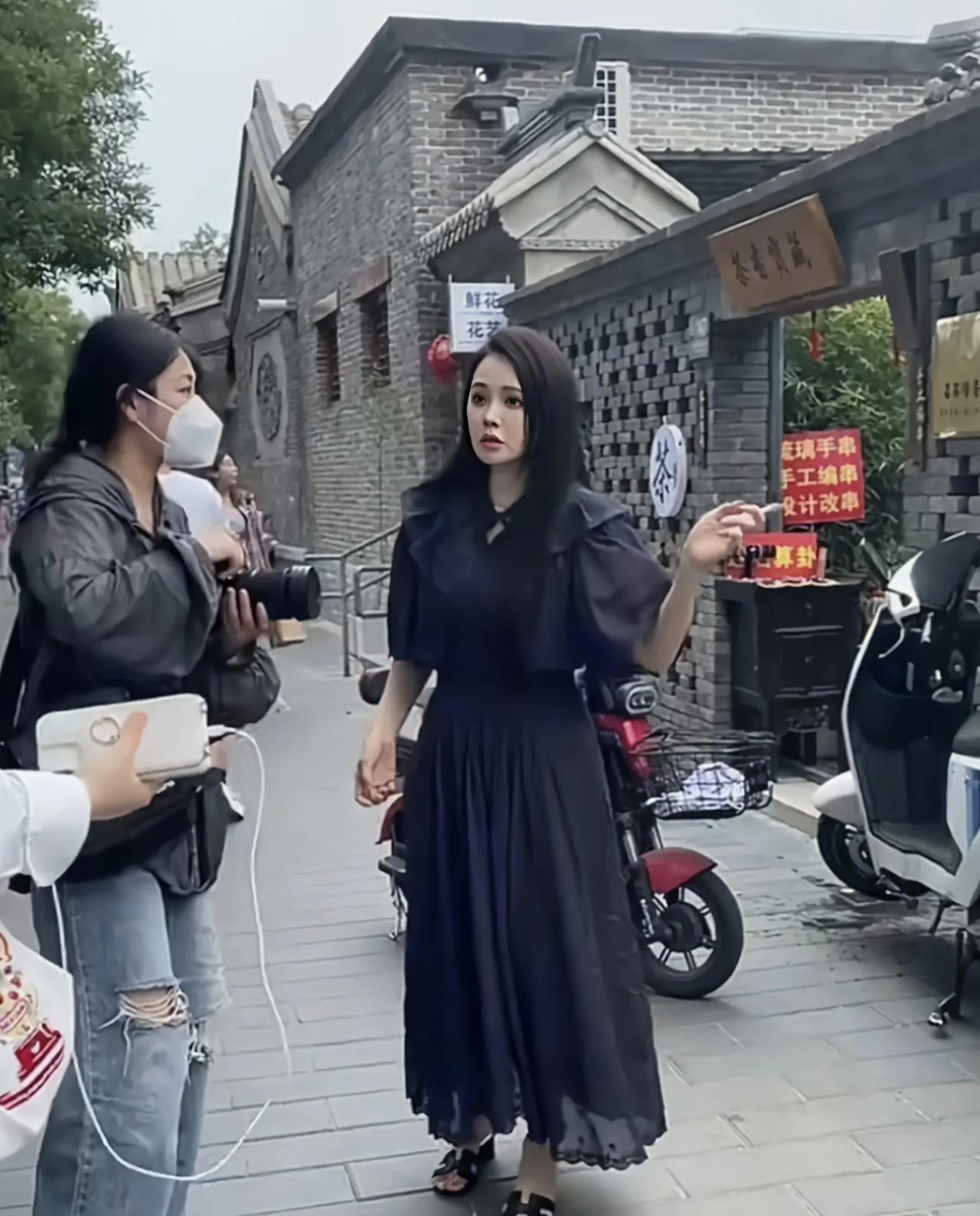 路人镜头下的伊能静，身穿连衣长裙，化着精致妆容，长发飘飘的她，一点也不像五十多岁