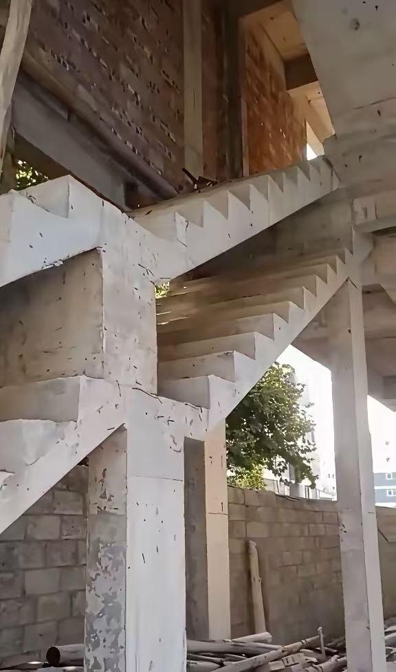 这是一处在建自建房的施工现场，画面里的两层水泥楼梯上下完全叠加在一起，属于典型的