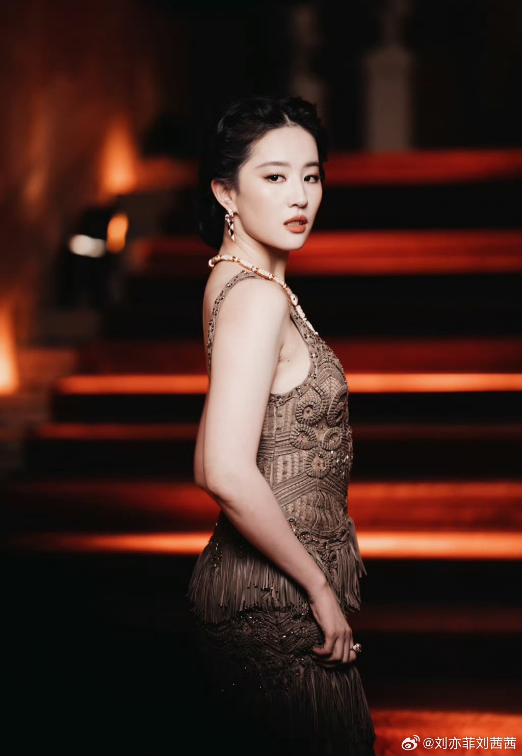 刘亦菲身着咖色流苏镂空深V礼裙，深V领与大露背设计大胆勾勒肩颈线条，层叠流苏随身