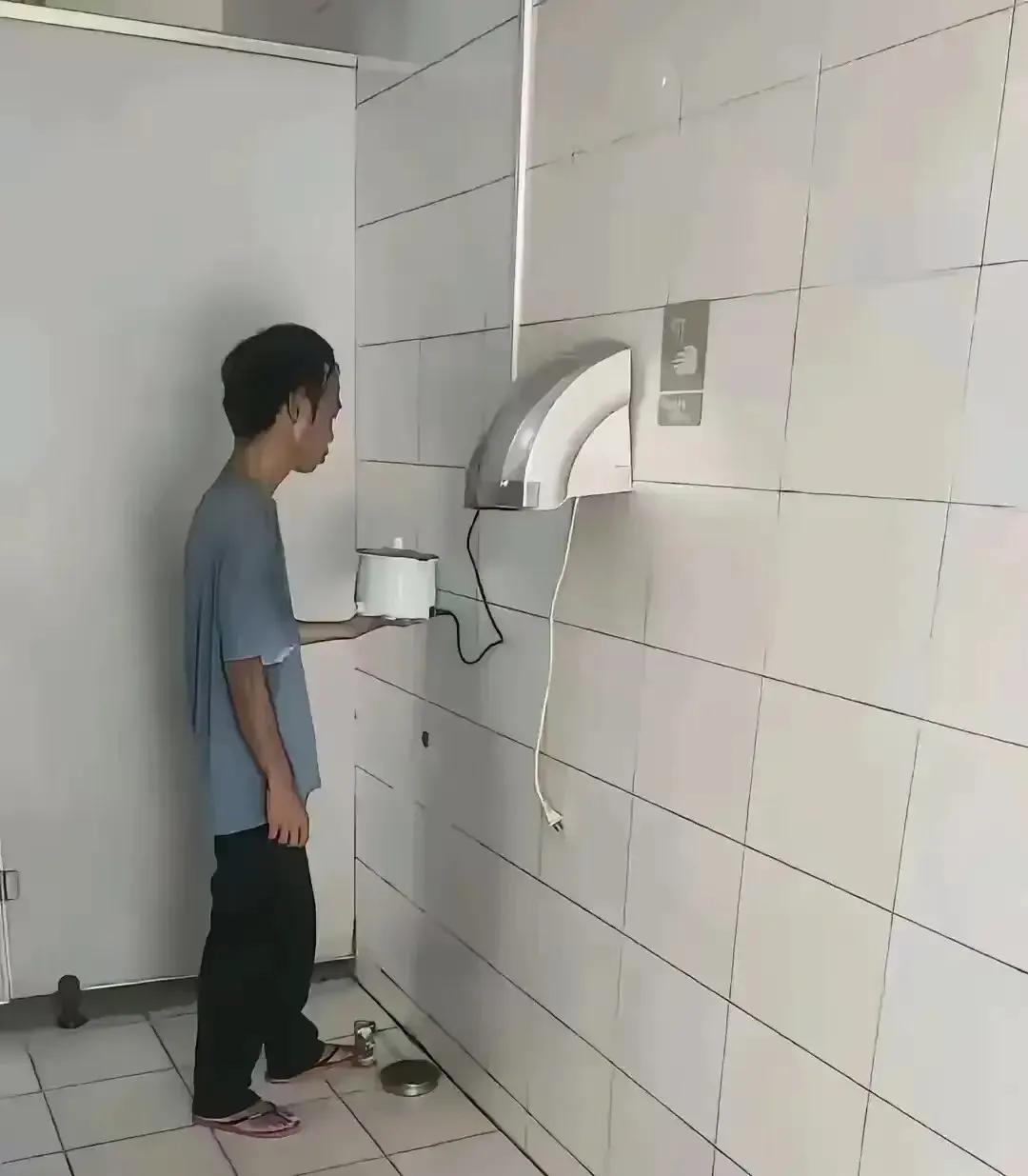 图上这位年轻人，每到饭点，就端着一个小电饭煲进厕所，把暖手机的插头拔掉，自己全程