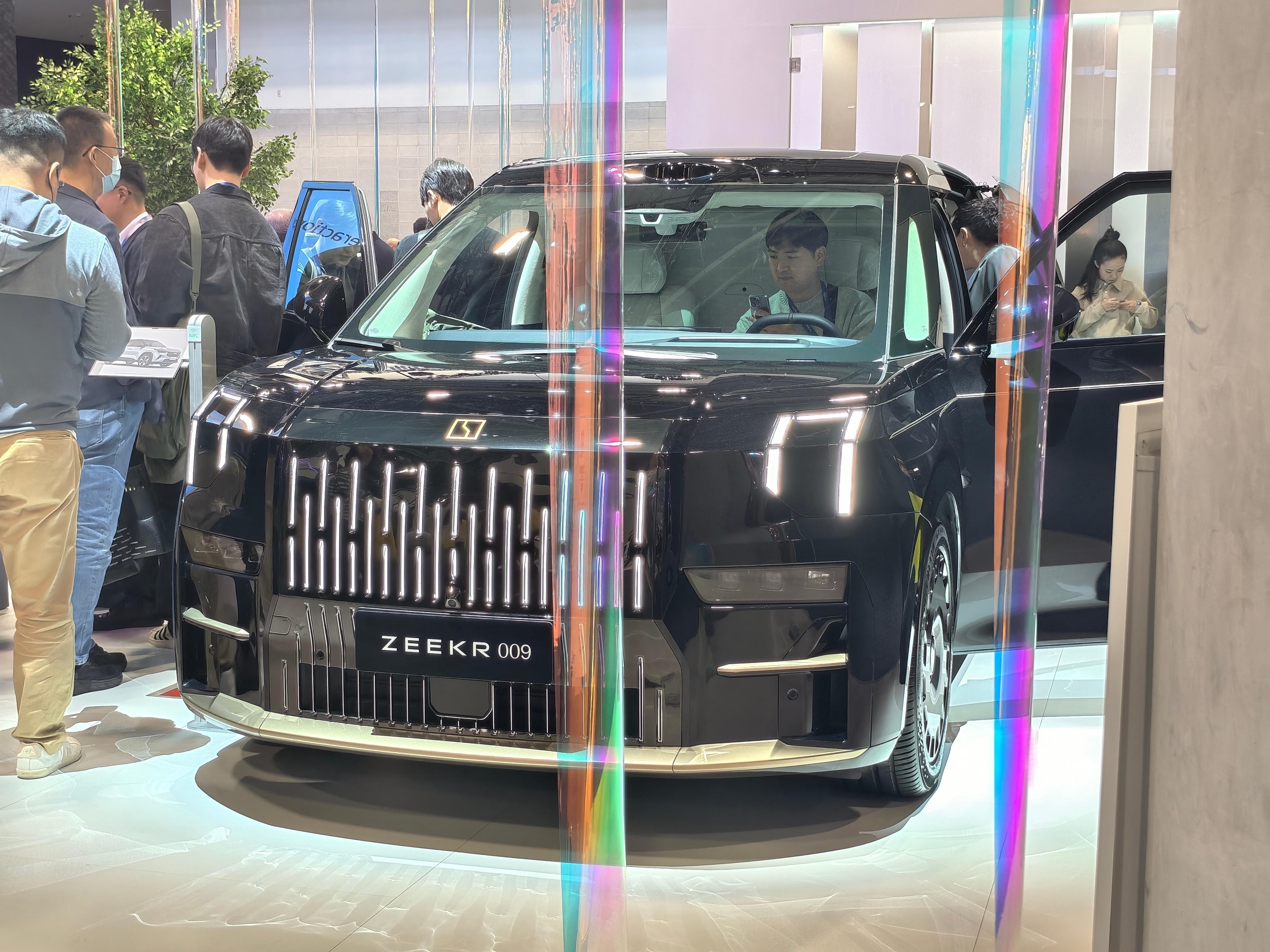 车上的老外在拍极氪 9X 和 009 光辉，车下的我在拍老外。他们为啥对这俩车这