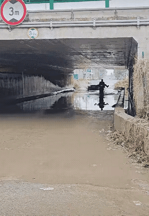 一名男子骑着一辆摩托车从一个桥洞经过的时候，下面还存留着一些下过雨留下的积水。这