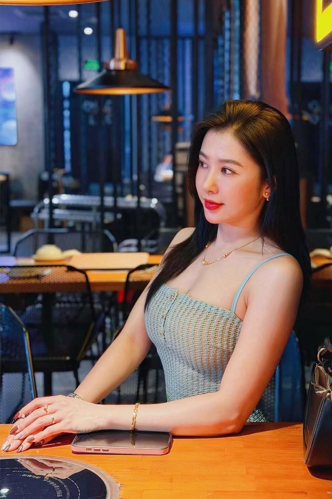 《晚灯娇姿》
浅绿罗裙趁晚风，灯痕暖处笑相逢。
木墙斜倚清姿立，一缕春娇入眼浓。