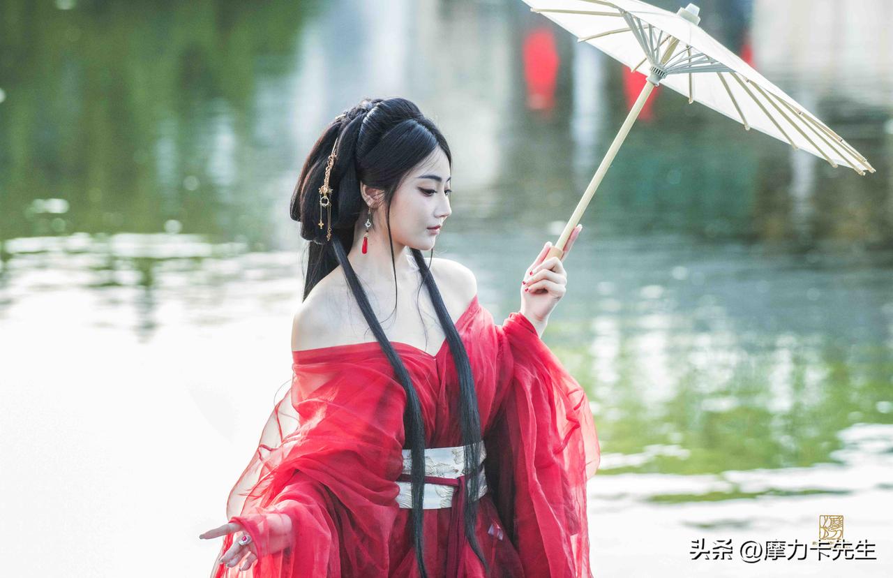 一袭红衣临水立，素伞轻擎，惹得水光也染上几分温柔。青丝垂落，风过处，是古意里走出