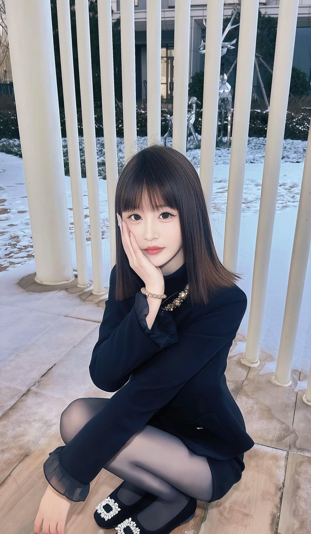 冬日暖阳下，黑衣少女静坐，温柔微笑，岁月静好。