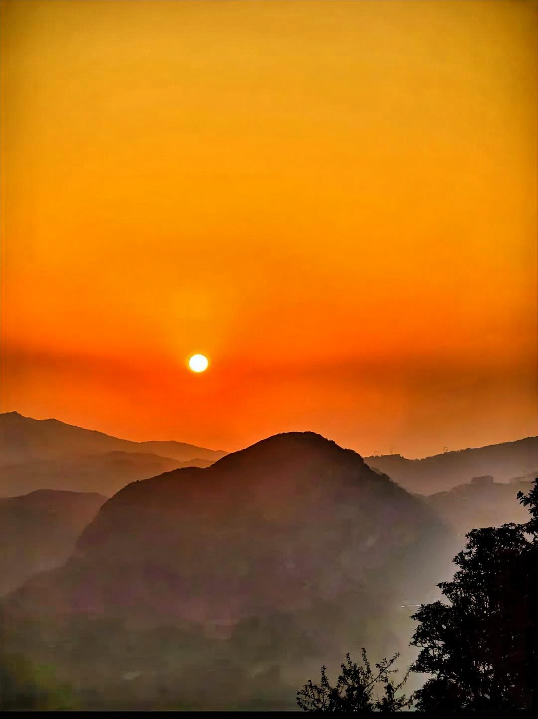日落之际，山峦连绵起伏，橙霞布满天空，静谧又美丽。橙红色的霞光宛如被一只无形的巨