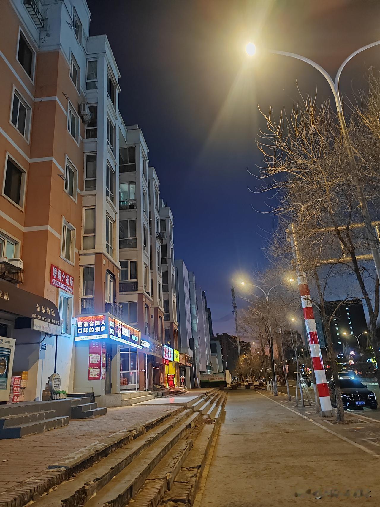 晚上溜达，直接被这画面戳中了！

橙白相间的居民楼立在街边，楼下小商铺的灯牌亮晃