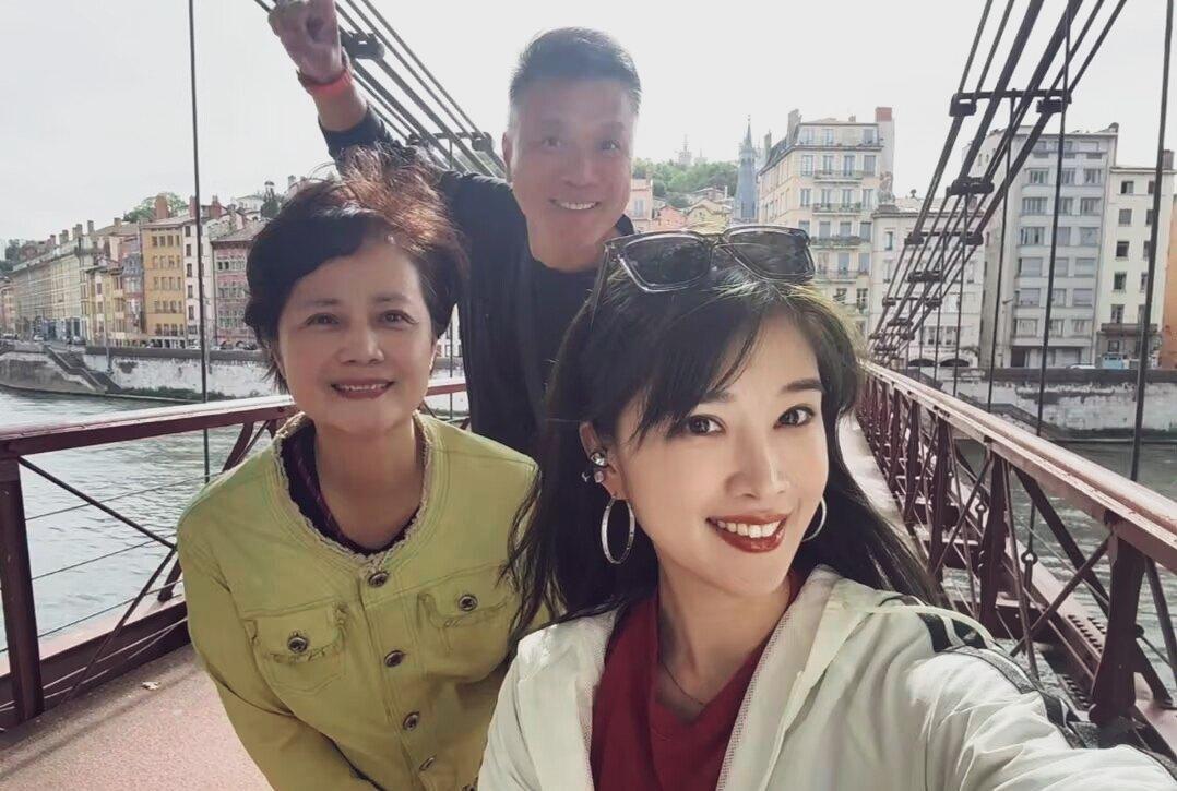 法国里昂索恩河吊桥上。女演员奚望与母亲茹萍，继父刘之冰一家人的自拍照。
妈妈漂亮