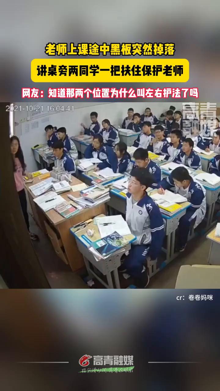 老师上课途中黑板突然掉落，讲桌旁两同学一把扶住保护老师。
卷卷妈咪。
网友：知道