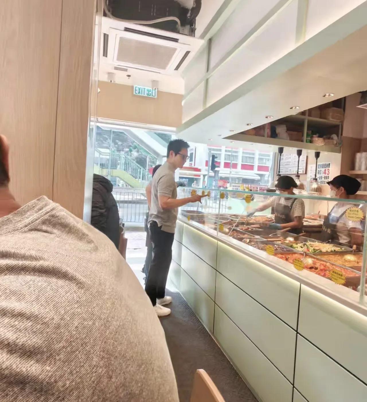 56岁郑嘉颖在香港一间快餐店买菜，他接完孩子放学回家一个人出来买快餐，他拿着取号