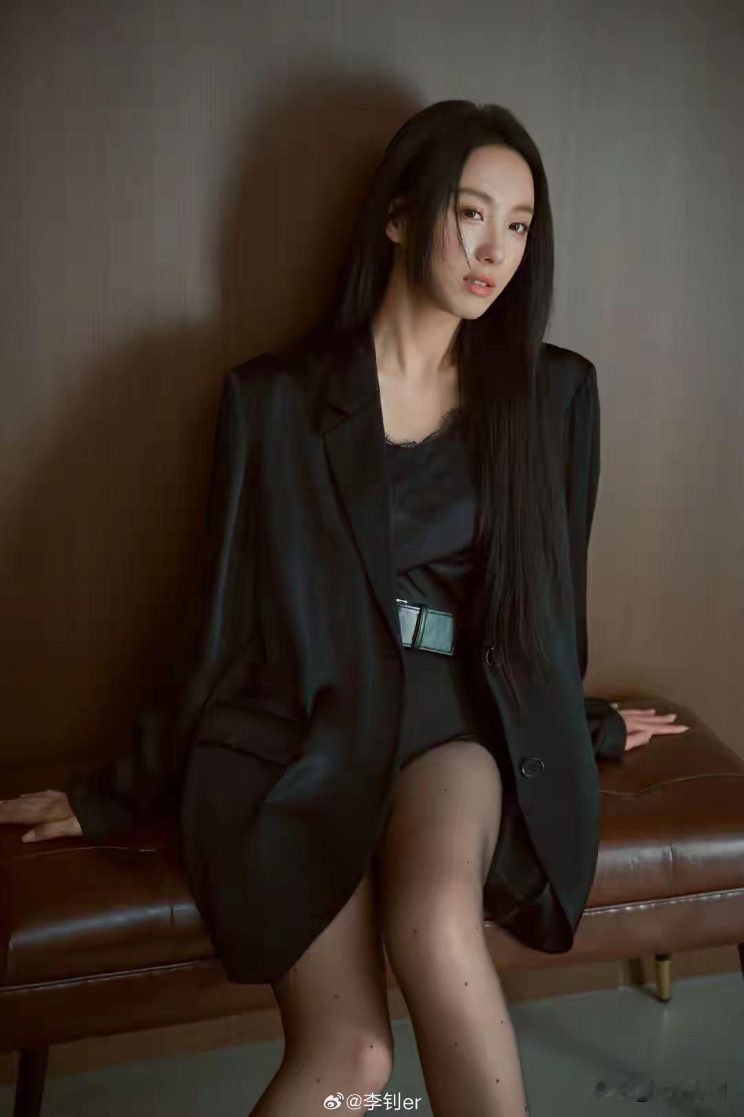 这位女士穿着黑色套装，坐在椅子上。上联：湖南湖北湖对湖， 下联： 在花前如何拍照