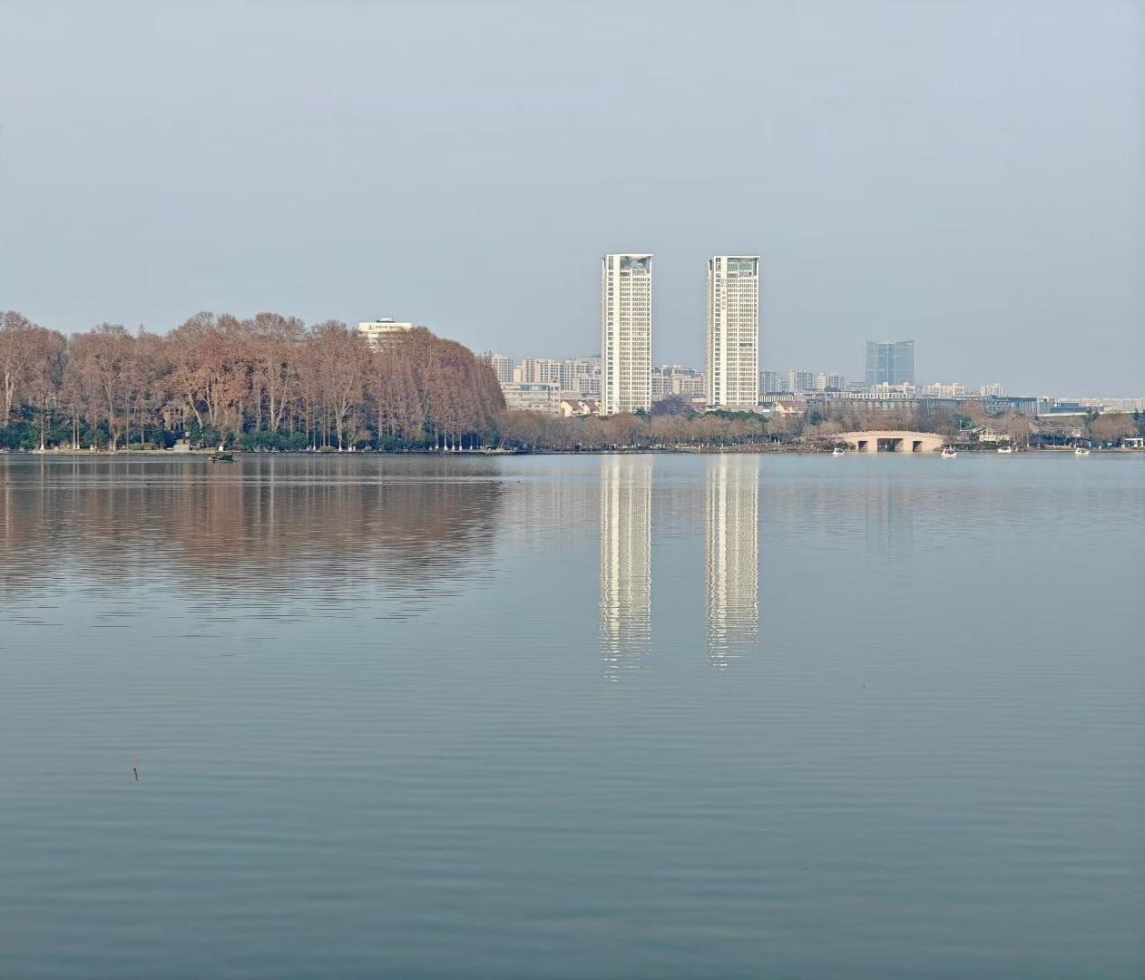 湖水把高楼与树影都熨成丝缎，天空是浅灰的绒布，整座城都在这方镜面里，睡成了，关于