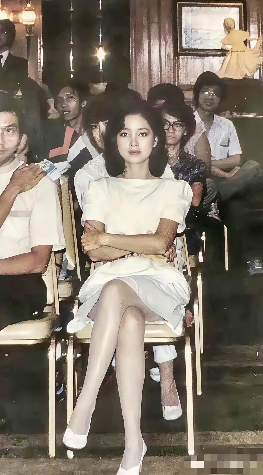 她是80年代公认的"最美港星"。这张旧照里，一袭白裙，双臂轻抱，眼神清澈又带着几
