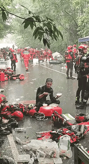 大雨滂沱地下着，而早已饿坏了的人民子弟兵战士，也只能在这样艰苦的环境下用餐，他们