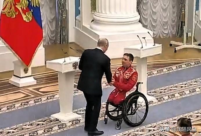 俄罗斯总统普京单膝跪地，向残奥会冠军、滑雪运动员伊万·戈卢布科夫颁发荣誉勋章。