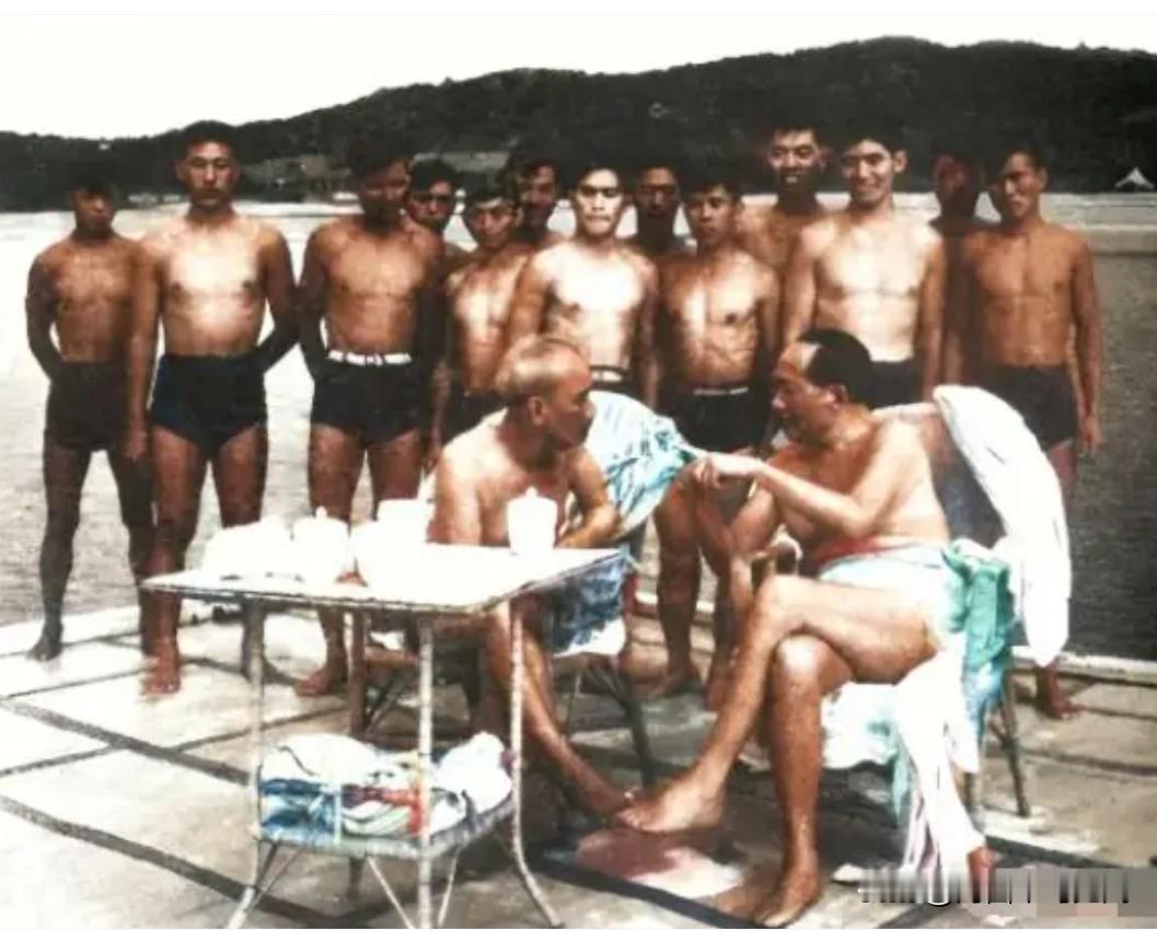 这是伟人游泳之后，在海边藤椅休息时，与友人坐着亲切交谈的一张珍贵合影。身后一排是