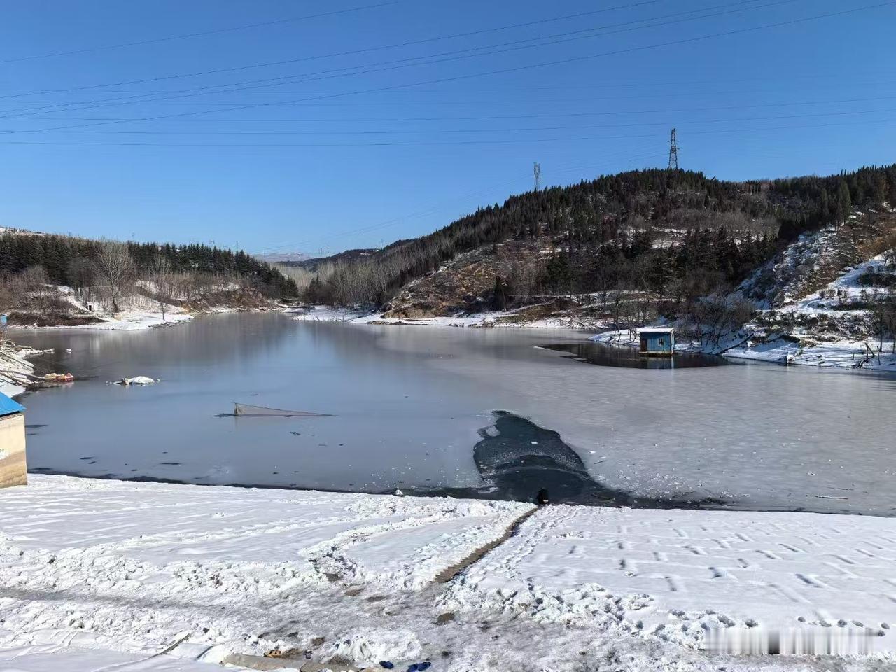 大雪过后的湖水，
有一半要结冰了，
山水之间的雪景，
远看还是非常壮丽的，
湖水
