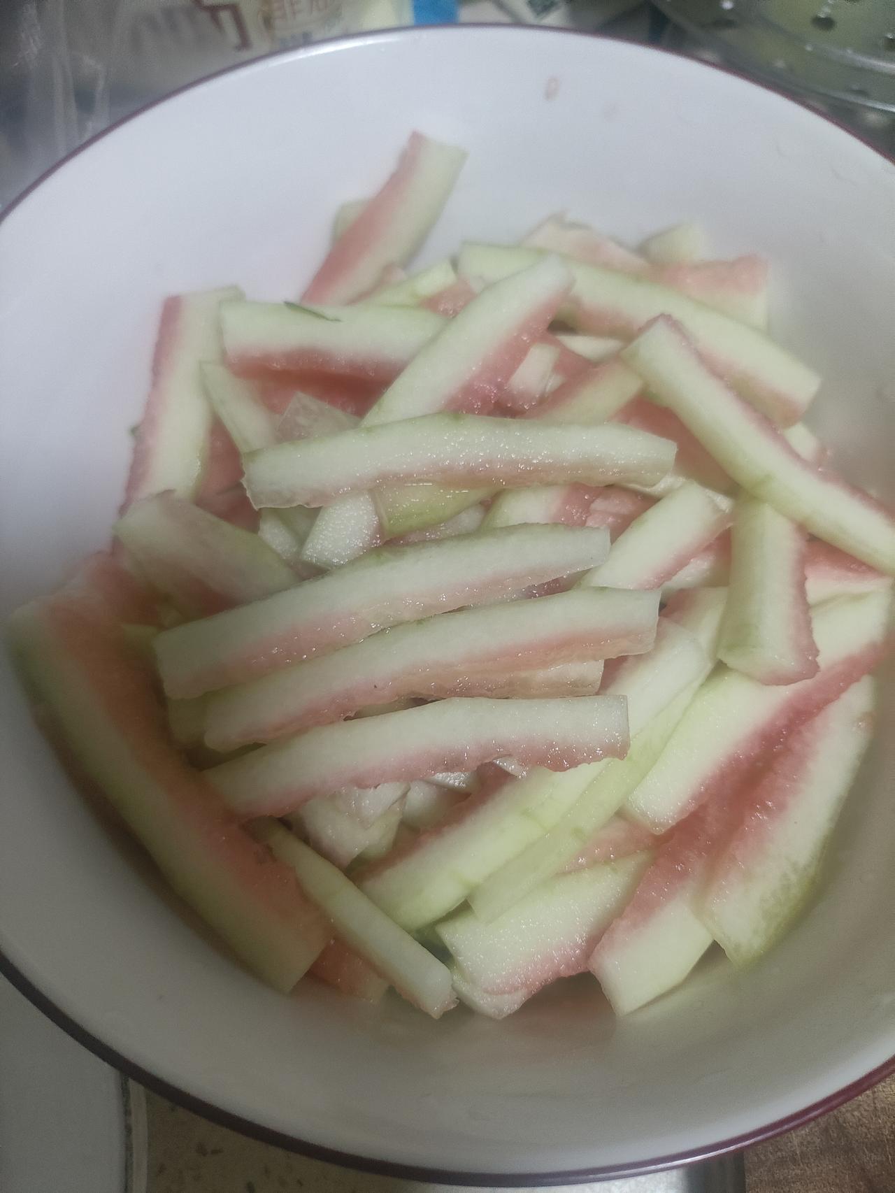 夏天就爱这口西瓜皮
把绿皮仔细切除
然后切成长条
用盐巴抓出水分
放入酱油，小米